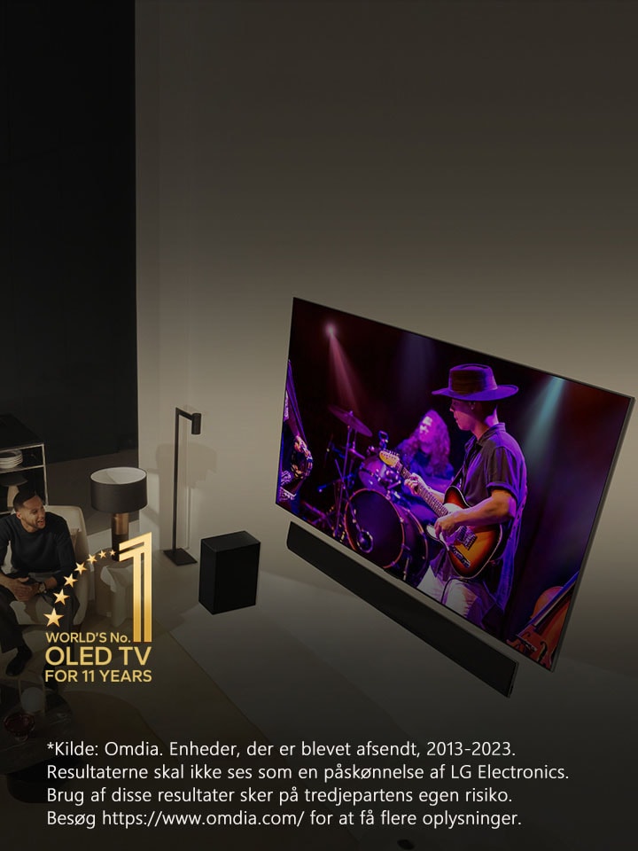 Visning oppefra af en mand og en kvinde, der ser en koncert p? et stort OLED TV i en moderne lejlighed. Emblemet “Verdens f?rende OLED TV i 11 ?r” ses p? billedet. En ansvarsfraskrivelse frems?tter: “Kilde: Omdia. Enheder, der er blevet afsendt, 2013-2023. Resultaterne skal ikke ses som en p?sk?nnelse af LG Electronics. Brug af disse resultater sker p? tredjepartens egen risiko. Bes?g https://www.omdia.com/ for at f? flere oplysninger.”	