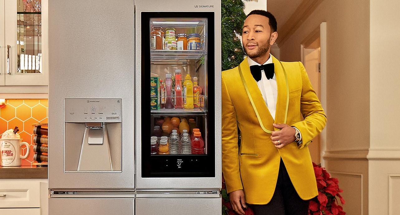 El cantante John Legend apoyado en un refrigerador LG SIGNATURE.