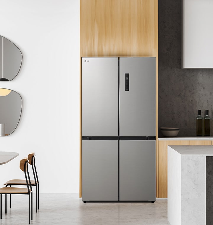 Cocina moderna con frigorífico lg multipuertas en un elegante acabado plateado, acompa?ada de una mesa de comedor redonda con sillas de madera, que incluye espejos abstractos y mobiliario minimalista.