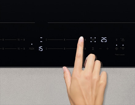 Une personne touche le panneau de contr?le de la plaque induction.