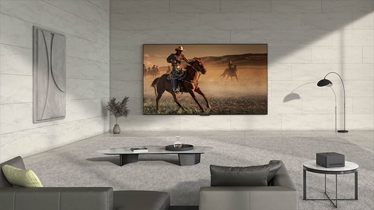 La vidéo s'ouvre sur le LG OLED M3 accroché au mur d'une pièce, avec des fils et des périphériques en pagaille connectés à la télévision. Une ligne bleue se déplace sur l'écran, les fils et les appareils disparaissent, puis la Zero Connect Box appara?t sur une table d'appoint. L'écran devient noir, ne laissant appara?tre que la télévision et la bo?te, en soulignant leur emplacement. La bo?te et la télévision se déplacent vers deux autres endroits de la pièce et, à chaque fois, l'écran devient noir pour mettre en évidence leur emplacement. 