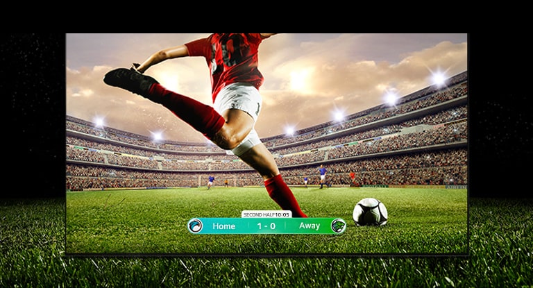 Image de l’écran diffusant un match de football avec un joueur portant un maillot rayé rouge qui s’apprête à tirer dans le ballon. Le score du jeu est visible en bas de l’écran. La pelouse verte du terrain s’étend au-delà de l’écran jusqu’à la toile de fond noire.