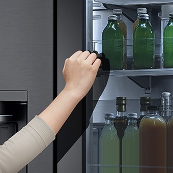 Vue avant du frigo InstaView à verre noir illuminé, avec des mains interagissant avec l’écran tactile en fa?ade