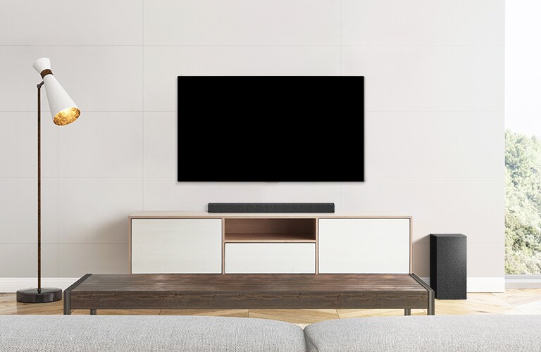 Un téléviseur, une barre de son et un caisson de basses installés dans un salon moderne.