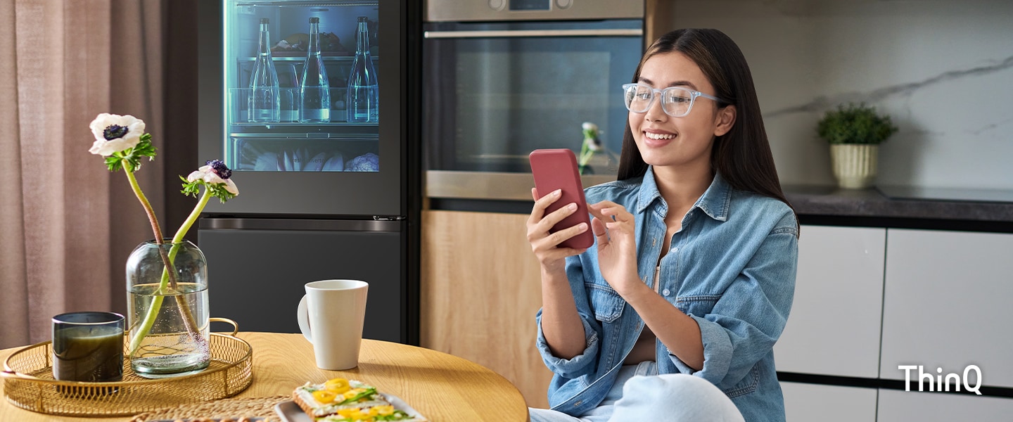 Une image d’une femme manipulant son téléphone dans la cuisine.