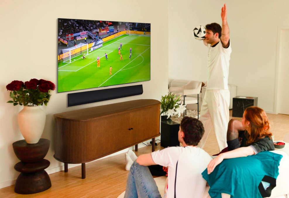 Janis Danner applaudit en regardant un match de foot avec des amis sur sa TV LG OLED G4.