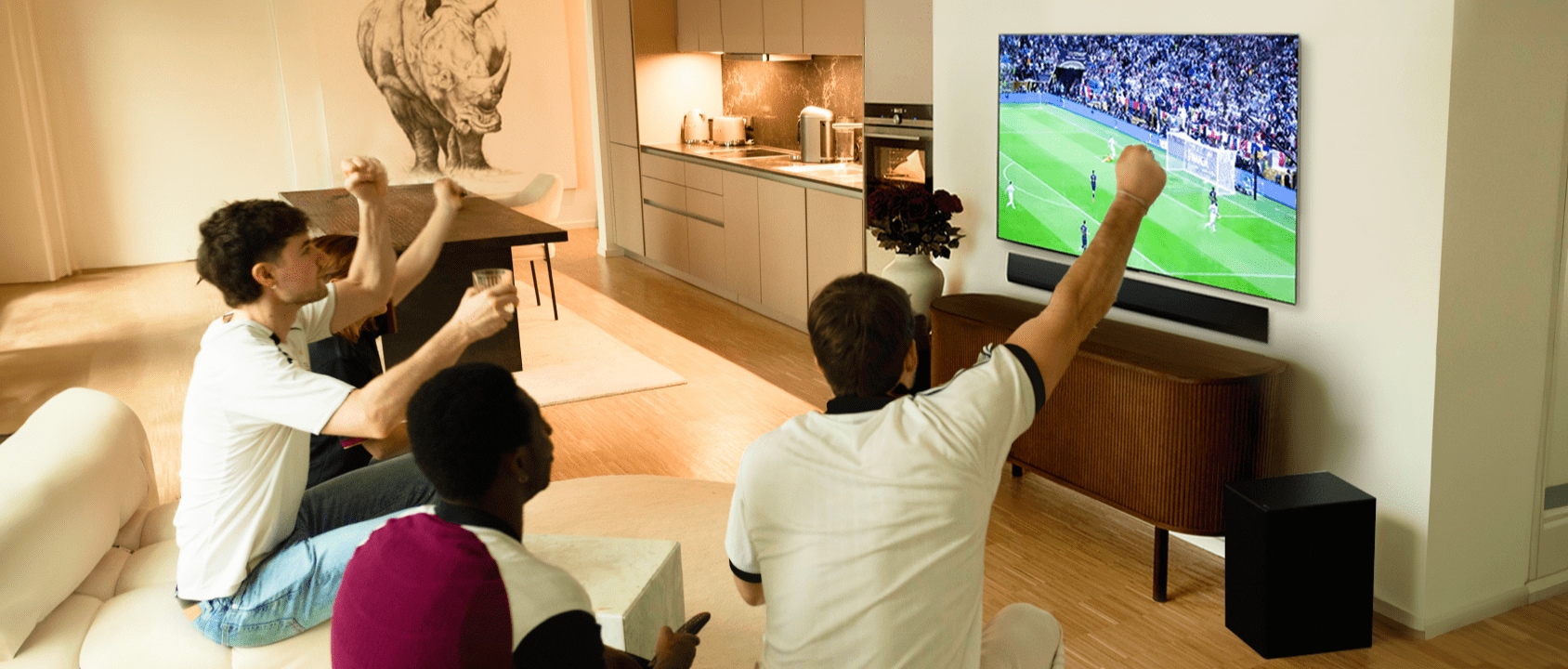Janis Danner applaudit alors qu'elle s'assoit sur le canapé avec ses amis et regarde un match de foot sur sa TV LG OLED G4.