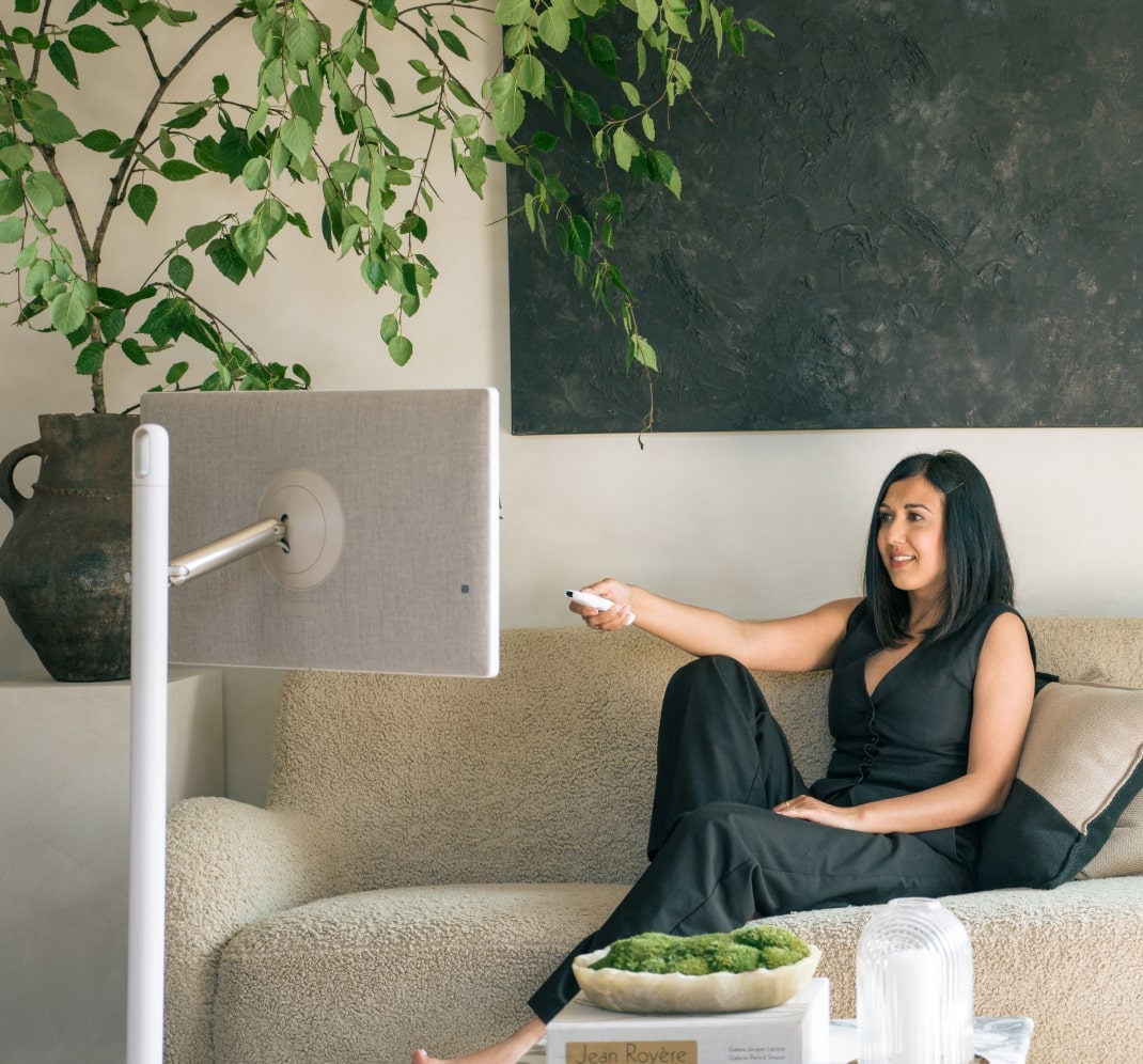 Lisa Mistry est allongée sur son canapé, souriant tout en utilisant la télécommande pour contr?ler le LG StandbyME.