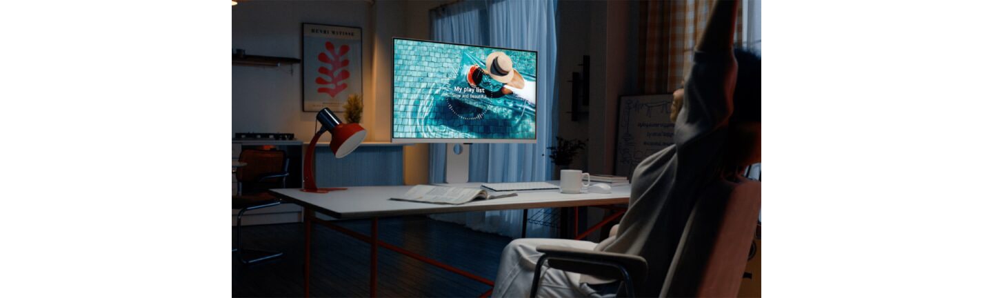 A user listening to a music playlist displayed on the LG MyView Smart Monitor at desk