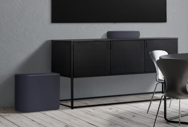 The black LG éclair and subwoofer placed below a wall-mounted LG TV to effortlessly blend into a grey contemporary living space