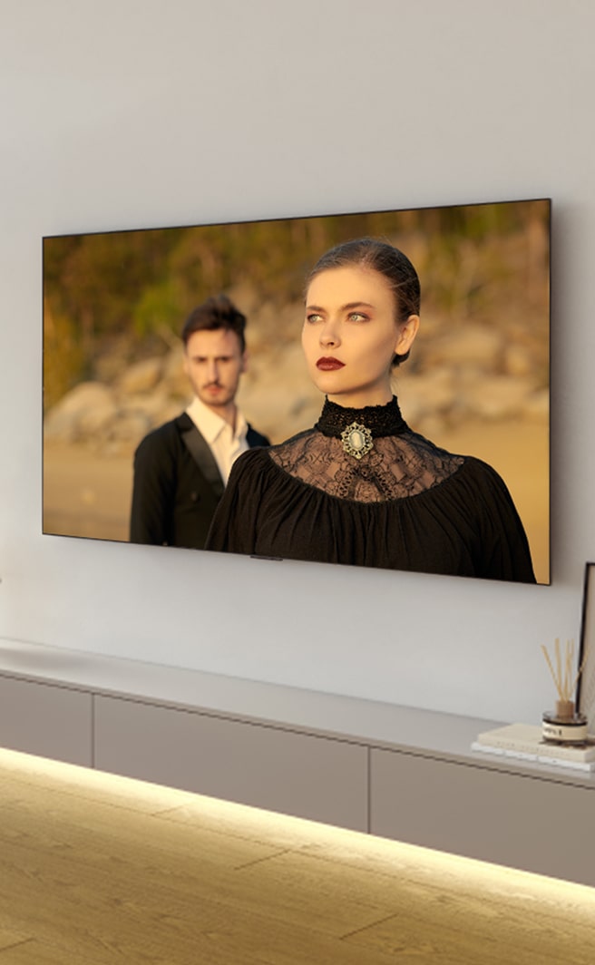 Egy n? filmet néz egy LG OLED TV-n egy nappaliban, mocktailt fog a kezében, egy LG InstaView h?t?szekrény áll a falon lév? TV mellett