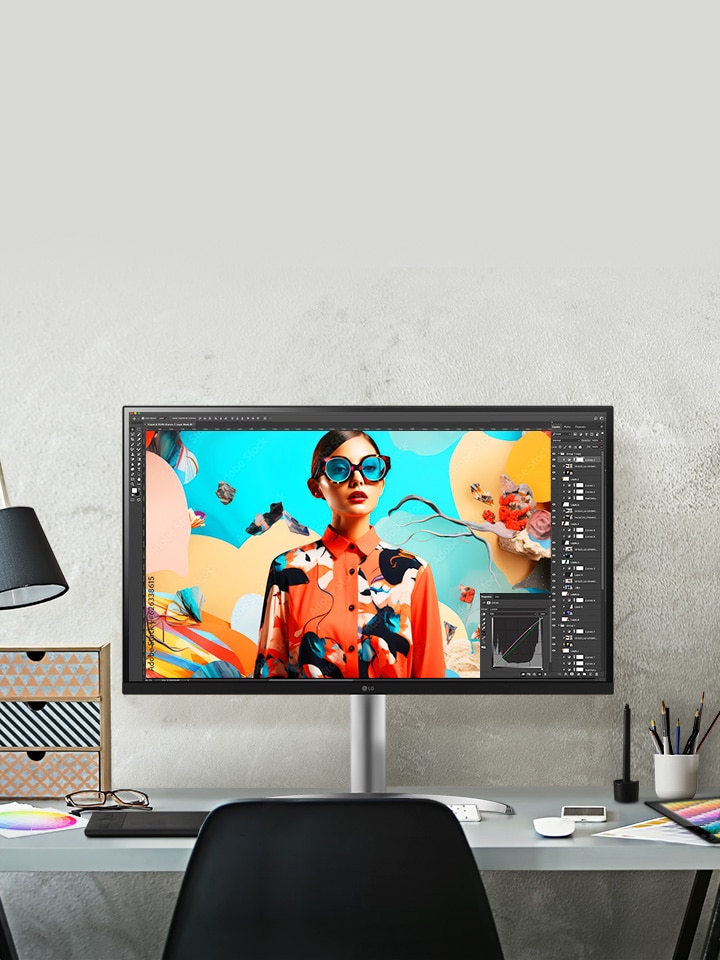 Egy dizájn stúdió asztalán UltraFine monitor látható a képerny?n Photoshop munka van folyamatban.
