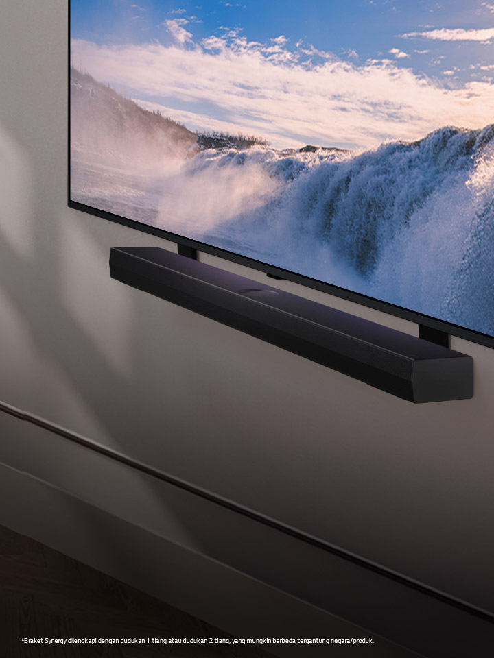 LG TV dan Soundbar ditempatkan dalam sudut pandang yang dipasang di dinding. Di TV, gambar air terjun besar ditampilkan dari dekat, dan sinar matahari lembut menyinari dinding, TV, dan soundbar. Penafian sebagai berikut: “Braket Synergy dilengkapi dengan dudukan 1 tiang atau dudukan 2 tiang, yang mungkin berbeda tergantung negara/produk.”