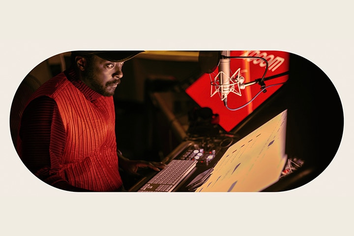 will.i.am che lavora in studio guardando uno schermo posizionato sotto un microfono.