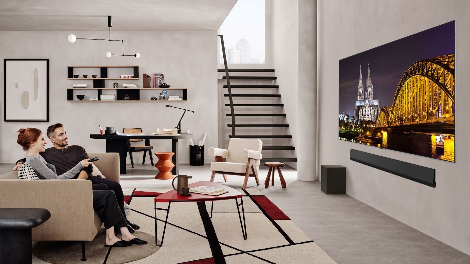 Acquistare un nuovo TV, la guida ai consigli: immagine di un salotto con due persone sul divano che guardano un programma su TV Oled Evo LG 