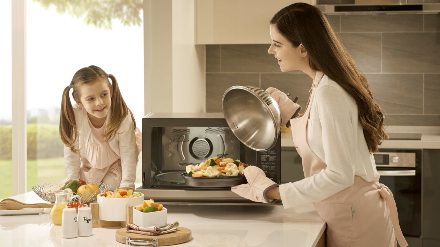 Come cuocere a vapore: immagine di una mamma e una bambina che cuociono verdure a vapore nel microonde.    ? 
