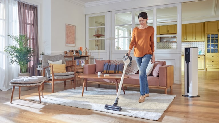 Organizzare le pulizie di casa: immagine di una donna che passa l’aspirapolvere