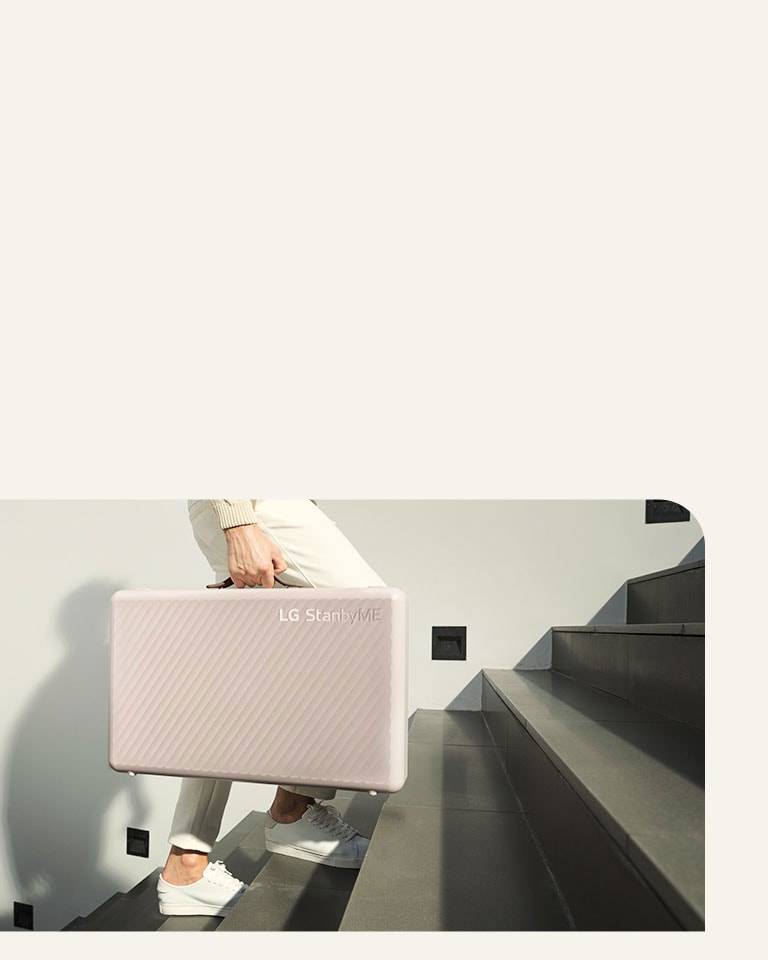 Un uomo trasporta comodamente LG StanbyME Go grazie al suo design a valigetta.