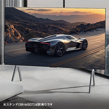Spacious living room with a view of a cityscape. LG OLED TV is on a stand. The Ultra Slim Design makes the screen feel immersive.  Zero Connect Box is visible, but concealed. 