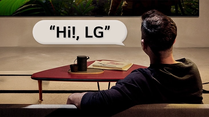 Une personne dans son salon. Une bulle de dialogue autour d’elle montre comment elle interagit avec sa LG TV en disant simplement ??Bonjour LG??.