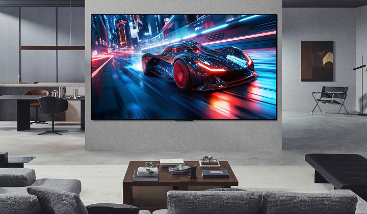 Salon avec une LG TV ultra large fixée au mur. à l’écran, on voit un jeu de course. En raison de la taille de l’écran, le contenu semble beaucoup plus immersif.