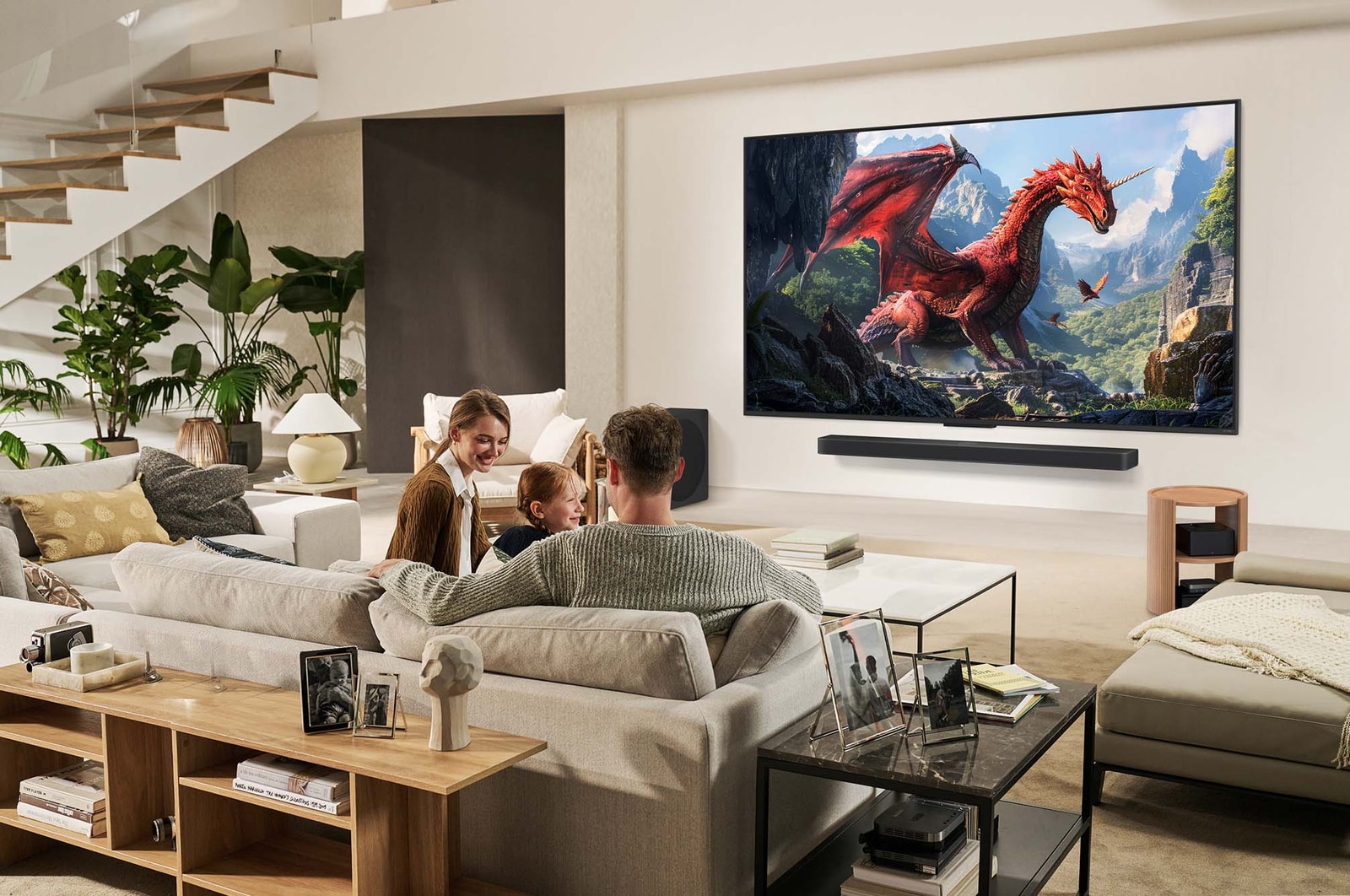 A family sits on a couch facing a LG QNED TV mounted on a wall above a LG Soundbar. Zero Connect Box sits inside a coffee table.