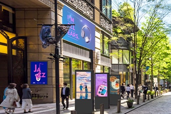 Esta imagen destaca la se?alización digital en un espacio exterior, donde se muestran diversos anuncios sobre temas como música, viajes y belleza.