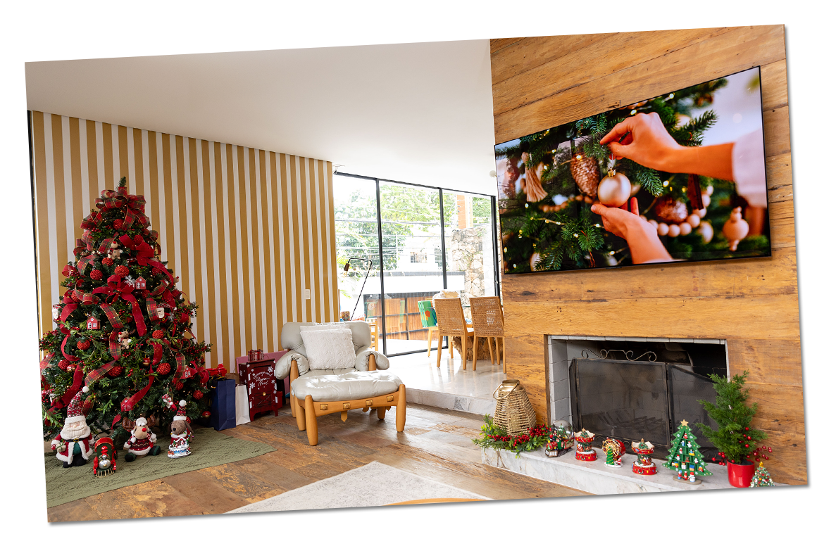Un árbol de Navidad está decorado en un cálido entorno festivo, mientras el televisor LG OLED muestra un video de decoración navide?a en la sala de estar.
