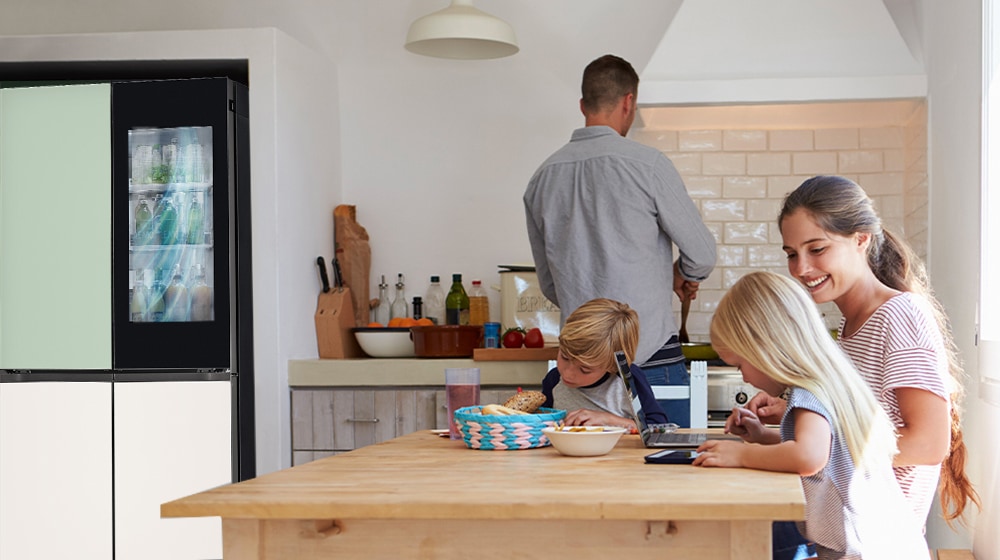 The whole family is sitting at the table preparing a meal. InstaView refrigerator installed on one side of the kitchen is creating cool air quickly.