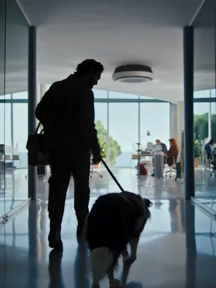 A man holding a dog leash heads to an office. 