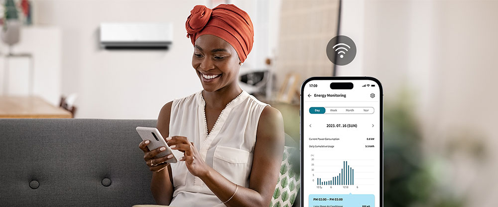 Een vrouw geniet van de koele wind van de airconditioner en controleert het energieverbruik via het scherm van de ThinQ?-app.