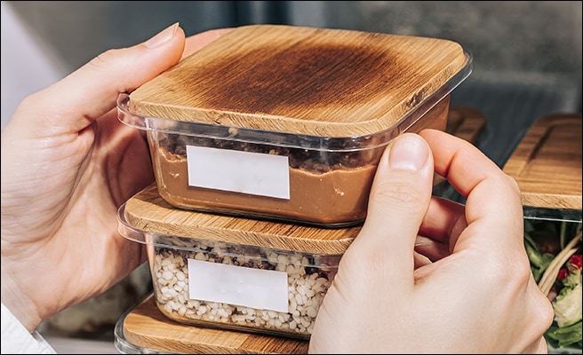 Twee beelden van de binnenkant van een koelkast gevuld met ingredi?nten en een stel dat in de keuken kookt