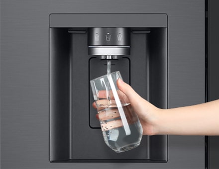  A person is getting water from the refrigerator dispenser in a cup