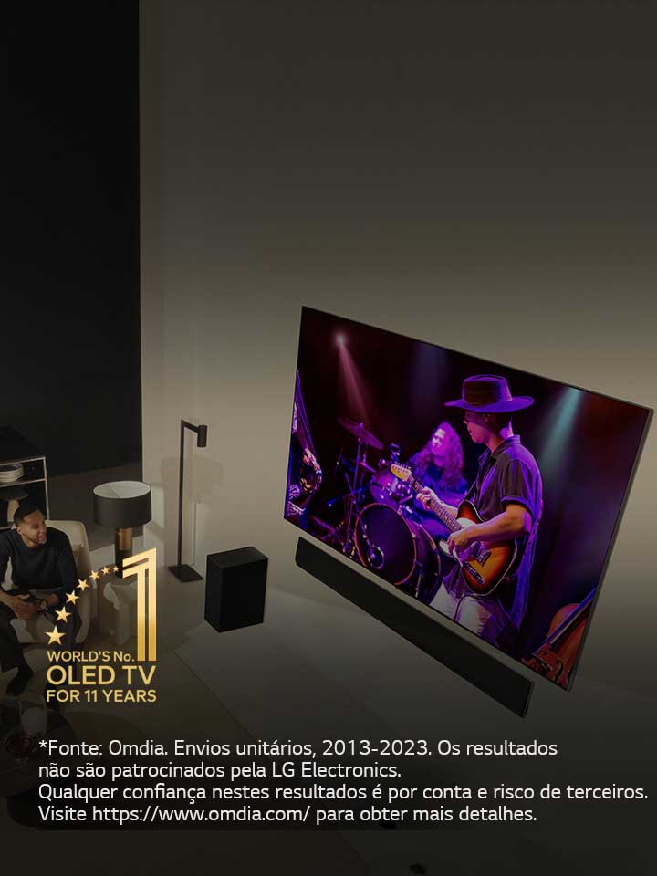 Uma perspetiva aérea de um homem e uma mulher a assistir a um concerto numa grande OLED TV num apartamento moderno. Aparece na imagem o emblema "A OLED TV número 1 do mundo há 11 anos". Uma declara??o de isen??o de responsabilidade diz o seguinte: “Fonte: Omdia. Envios unitários, 2013 a 2023. Os resultados n?o s?o patrocinados pela LG Electronics. Qualquer confian?a nestes resultados é por conta e risco de terceiros. Visite https://www.omdia.com/ para obter mais detalhes.”