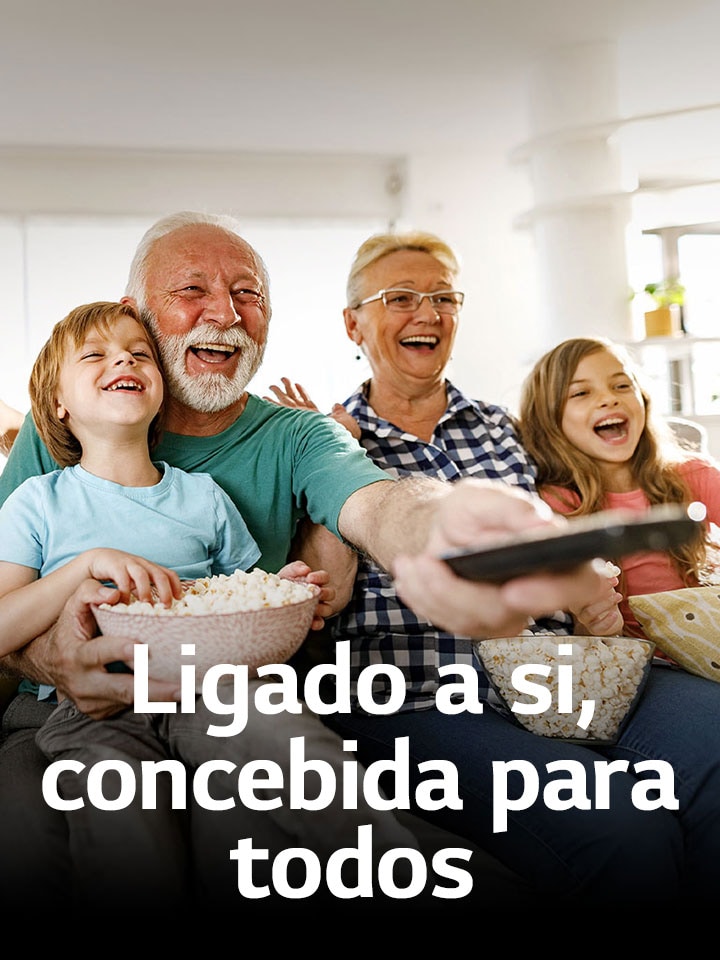 Uma família está sentada a rir enquanto o av? aponta o controlo remoto para o exterior.