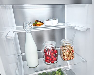 Alimentos em frascos encontram-se no interior do frigorífico e um deles é demasiado alto. Uma linha azul e setas indicam a possibilidade de dobrar a prateleira para ter mais espa?o.