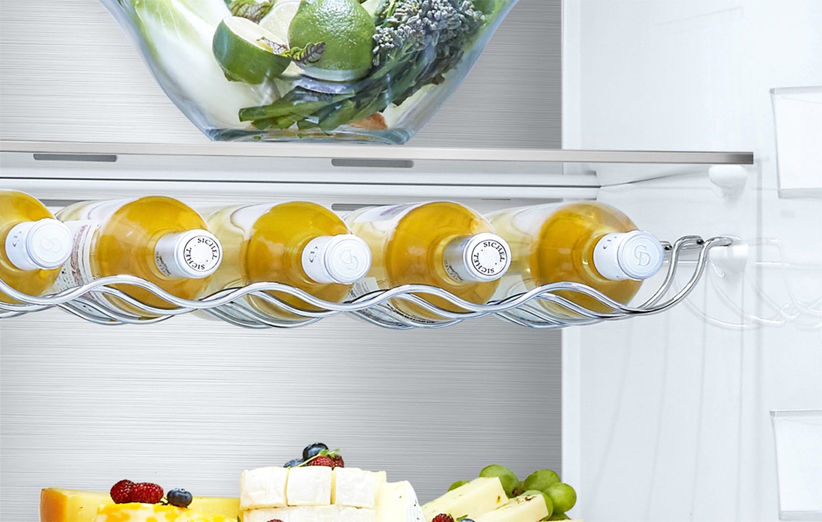 Cinco garrafas est?o no suporte, por baixo da gaveta, dentro do frigorífico com outros produtos nas restantes prateleiras.