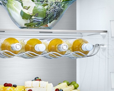 Cinco garrafas est?o no suporte, por baixo da gaveta, dentro do frigorífico com outros produtos nas restantes prateleiras.