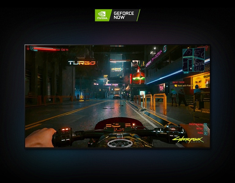 I en scen fr?n Cyberpunk 2077 som visas p? en LG OLED-sk?rm k?r spelaren p? en motorcykel genom en neonupplyst gata