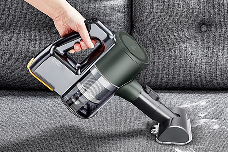 This image shows a Power Drive Mini being used to clean an animal hair and dusty sofa.