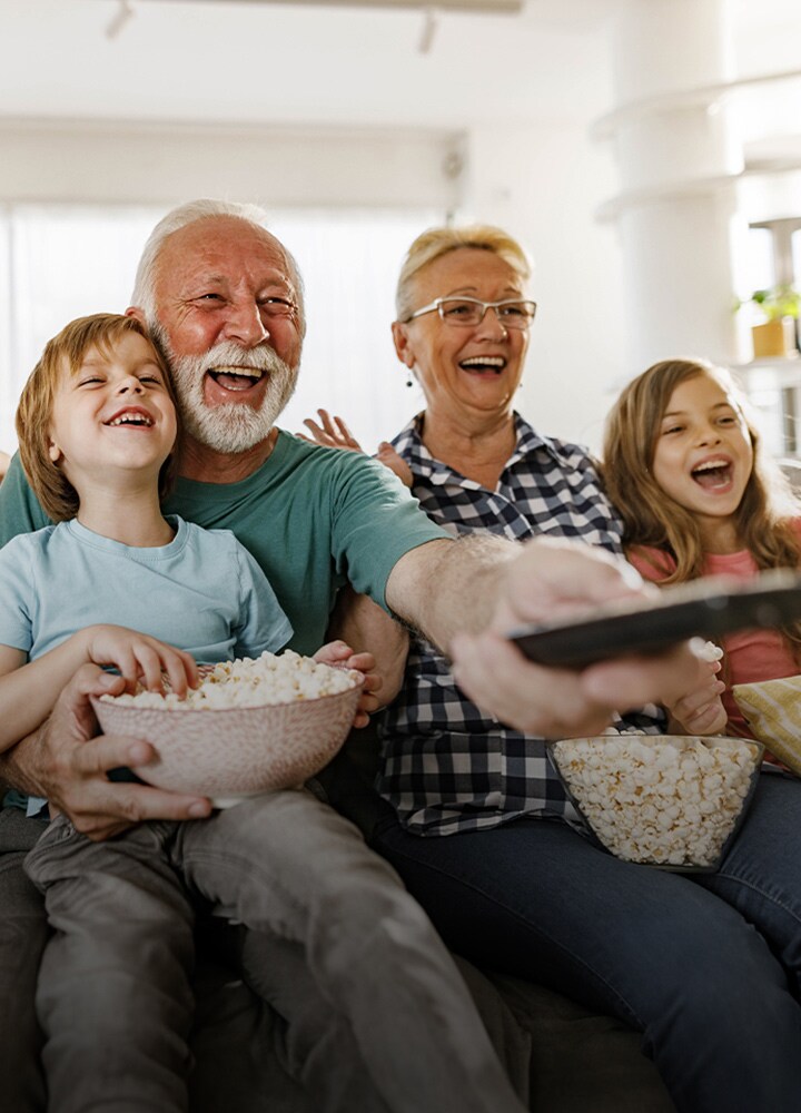 Gülerek birlikte oturan bir aile. Büyükbaba kumanday? d??ar?ya do?rultuyor.