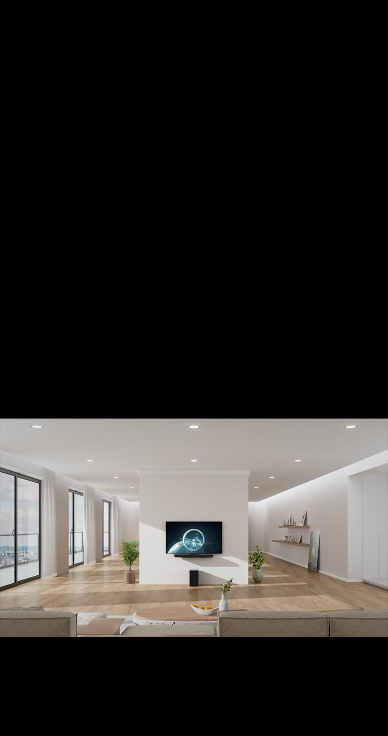 Soundbar ve TV, oturma odas?n?n ortas?ndaki beyaz kolona as?lm??t?r. Soundbar'?n hemen alt?ndaki ah?ap zeminde siyah bir woofer durur. Sol tarafta yerden tavana kadar uzanan, harika manzaral? pencereler ve beyaz perdeler vard?r. Sa? tarafta süslemeli ah?ap raflar vard?r ve yere bir resim yerle?tirilmi?tir.