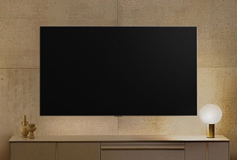 A wall-mounted LG TV looks powered down, but the Always Ready feature turns on. It shows information and then cycles through different artworks.	