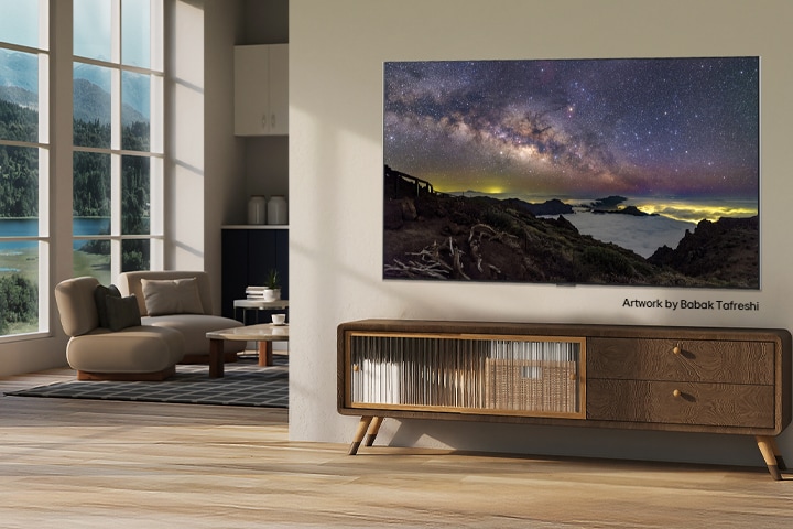 Interior of a countryside home. A huge wall-mounted LG TV is displaying a beautiful natural landscape artwork on its screen. The TV looks like a photograph hung on the wall. 	