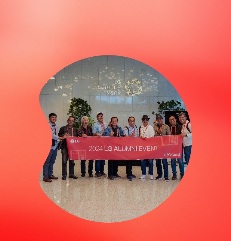 Group of people holding a banner that reads '2024 LG Alumni Event' in front of the LG Science Park. 	