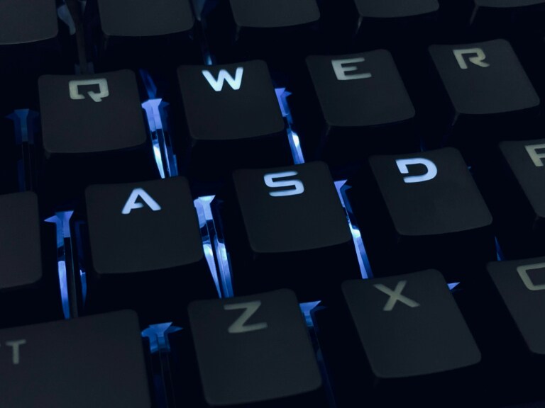 Close-up of a backlit keyboard with a focus on the keys Q, W, E, R, A, S, D, F, Z, and X illuminated in blue