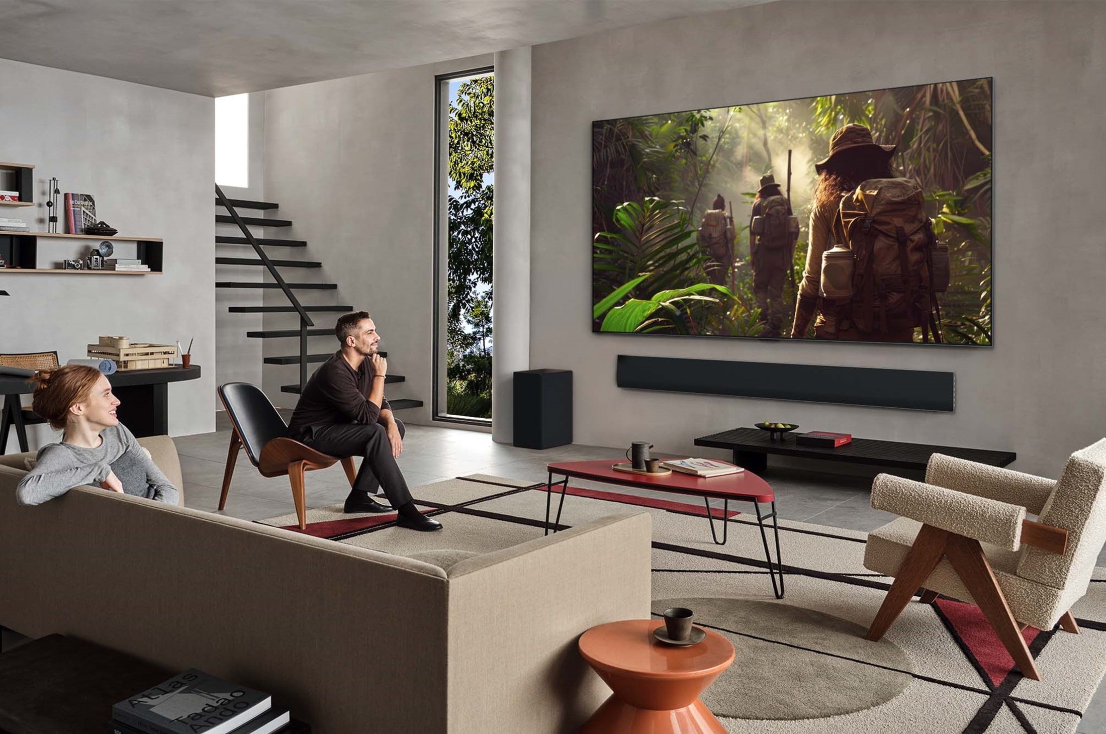 People are sat on sofas watching a TV show on their OLED TV