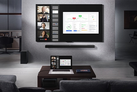 Phòng khách nhìn t? gh? dài, ??i di?n v?i TV LG True Wireless và LG Soundbar treo t??ng. Trên bàn cà phê là m?t chi?c máy tính xách tay ???c k?t n?i v?i H?p k?t n?i kh?ng day h?u nh? v? hình bên d??i bàn. Màn hình máy tính xách tay, hi?n th? cu?c g?i video tr?c ti?p, ???c ph?n chi?u kh?ng day trên màn hình TV. Toàn b? kh?ng gian g?n gàng và kh?ng có s? l?n x?n c?a day.