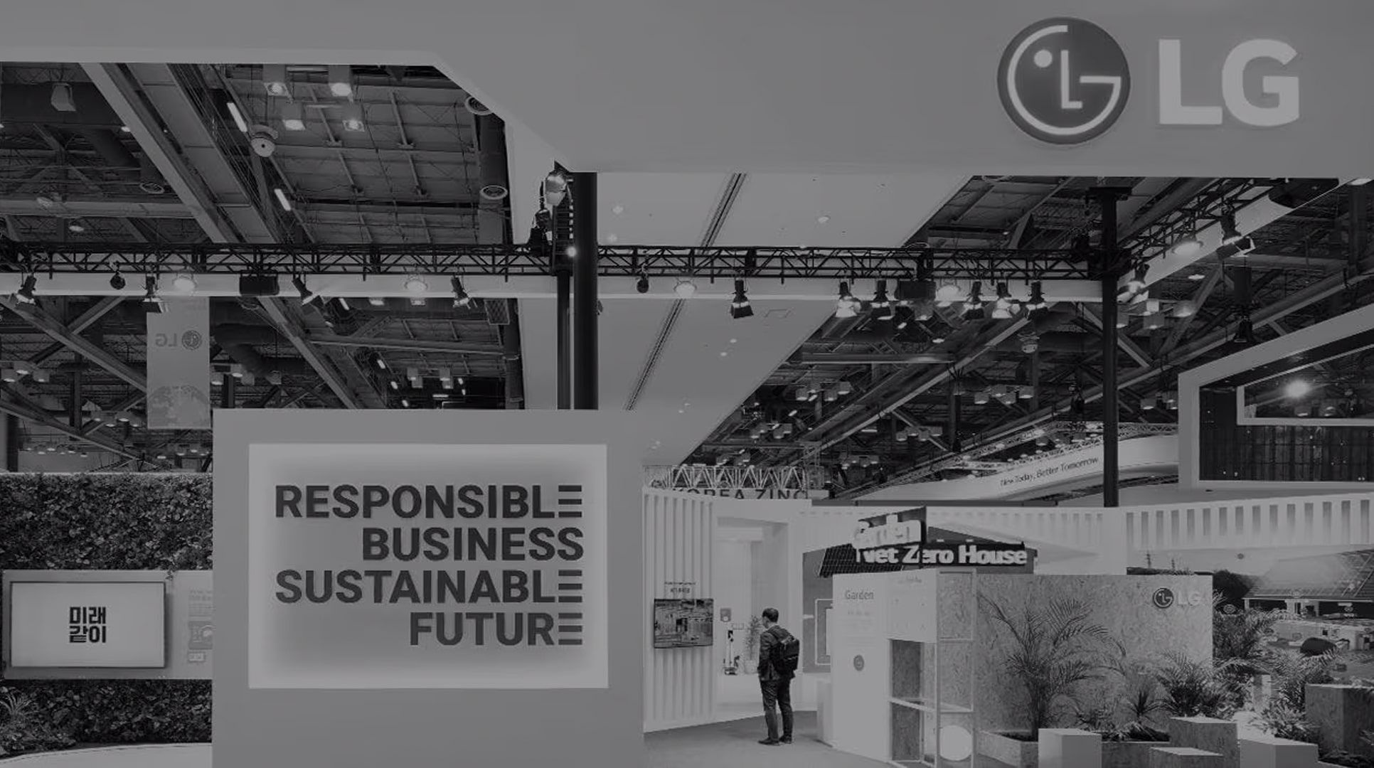 Là m?t hình ?nh ?en tr?ng, logo LG ? trên cùng bên ph?i và m?t ng??i ?ang ? trong gian hàng c?a Net Zero House. M?t s? cay ???c ??t c?nh t??ng.