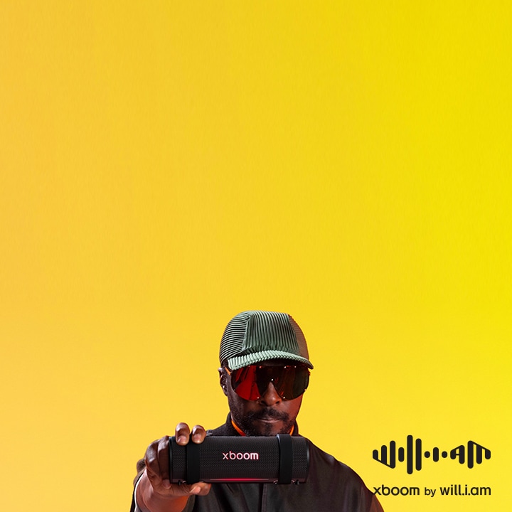 will.i.am trong trang ph?c ?en cùng kính ram cá tính, khoác chi?c xboom Grab trên vai ??y phong cách.